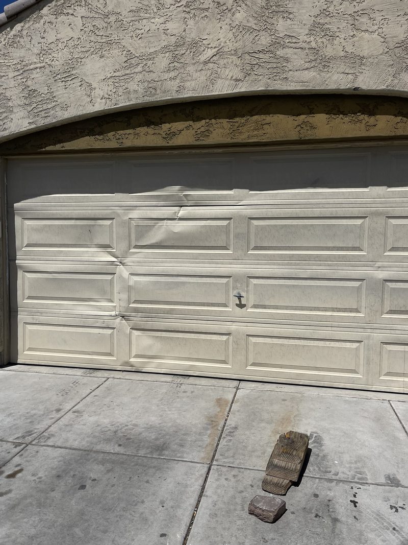 Garage door with panels bent inward from an impact