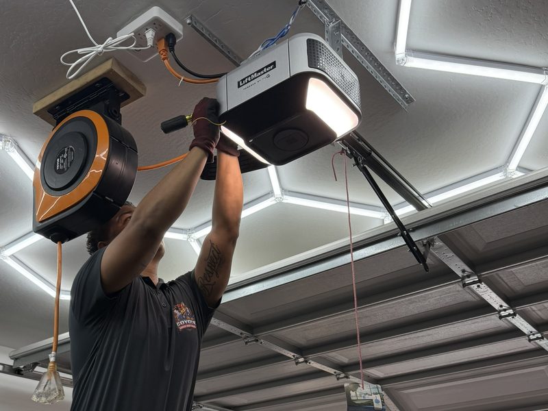 Eric Rivera installing a LiftMaster garage door opener, with the garage door open behind him