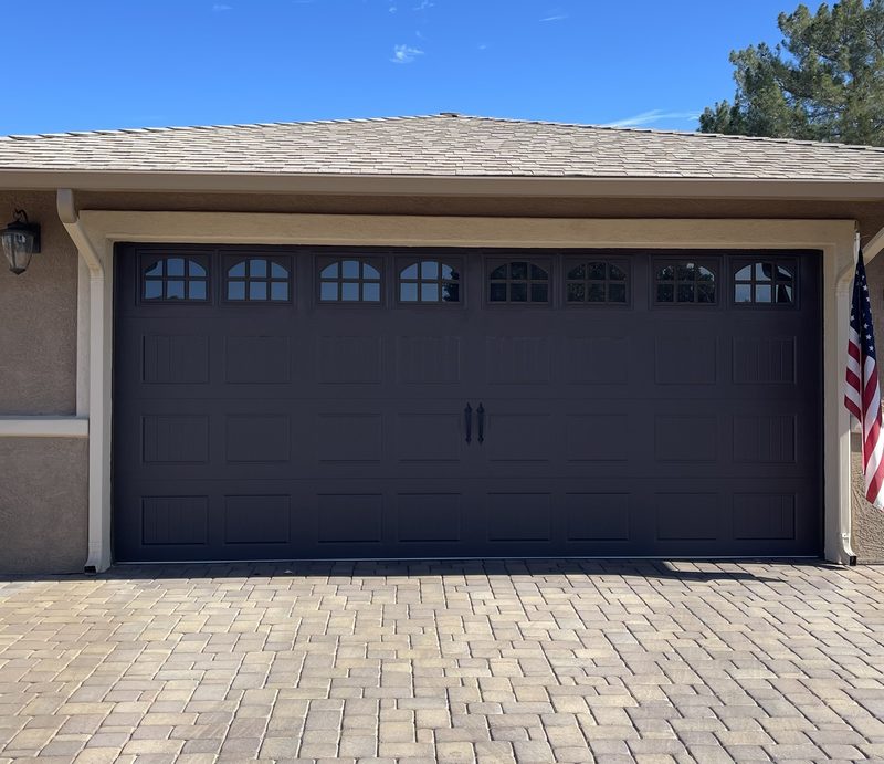 A new dark carriage-style garage door with arched windows, installed by Coyote Garage Door Service