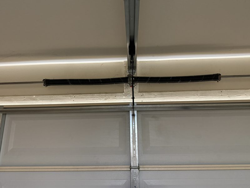 A pair of new torsion springs mounted above a garage door